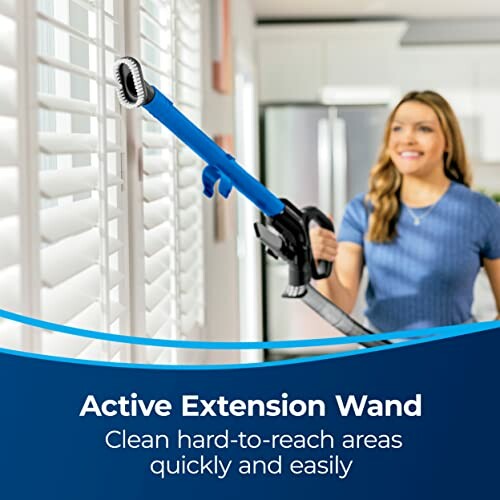 Woman using an active extension wand to clean window blinds.