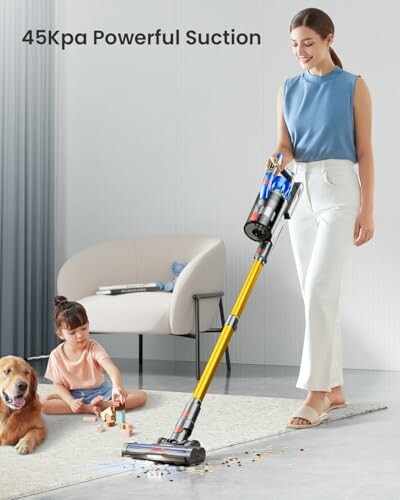 Woman using a cordless vacuum cleaner in a living room while child plays with dog.