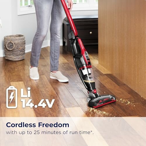 Person using a cordless vacuum cleaner on a wooden floor.