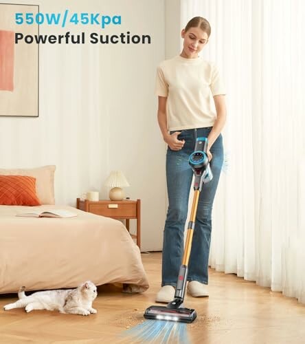 Person using a cordless vacuum cleaner with a cat nearby.