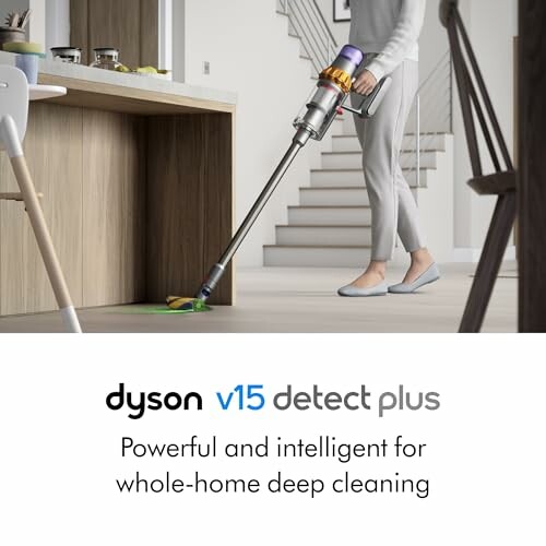 Person using Dyson V15 Detect Plus vacuum cleaner on hardwood floor.