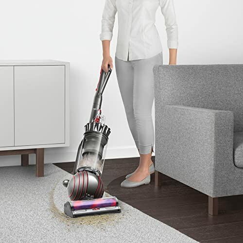 Person using a vacuum cleaner on a carpet in a modern living room.