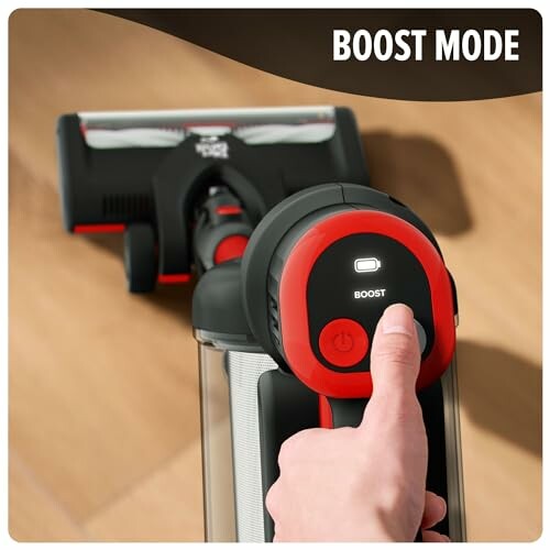 Hand pressing boost mode on a vacuum cleaner.