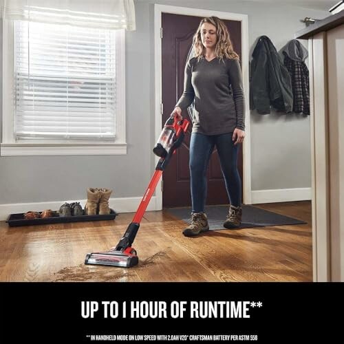 Person using a vacuum cleaner on a wooden floor.