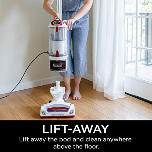 Person demonstrating vacuum cleaner lift-away feature on hardwood floor.