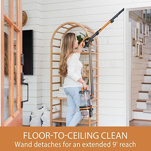 Person using a vacuum cleaner to reach high spots in a living room.