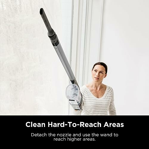 Person using vacuum cleaner wand to reach high areas.
