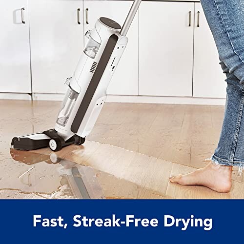 Person using a vacuum cleaner on wet floor for fast, streak-free drying.