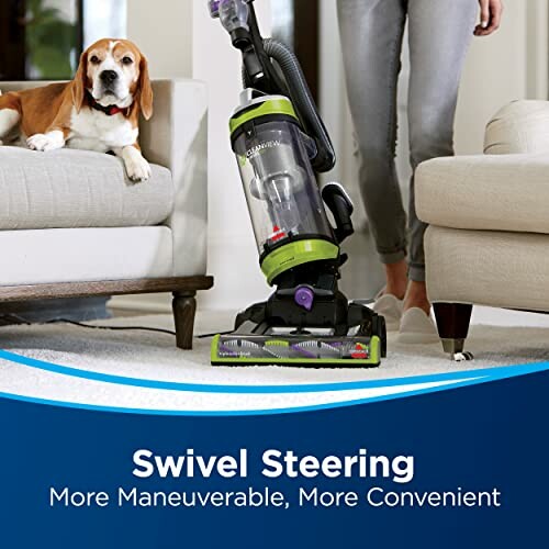 Person using a vacuum cleaner with swivel steering near a dog on a couch.