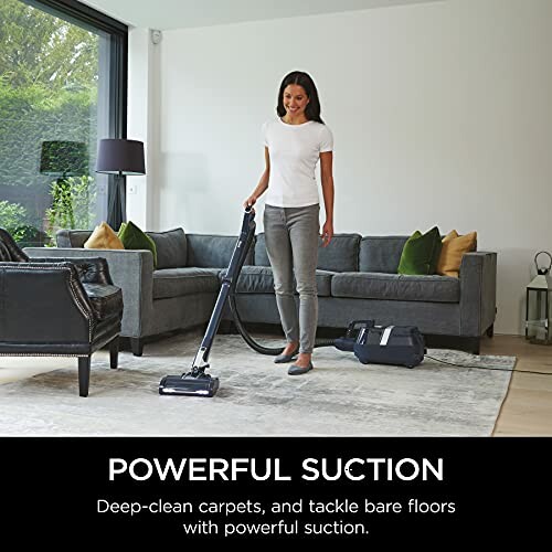 Person using vacuum cleaner in modern living room.
