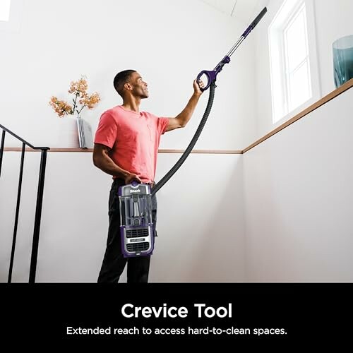Person using a vacuum crevice tool to clean a high window.