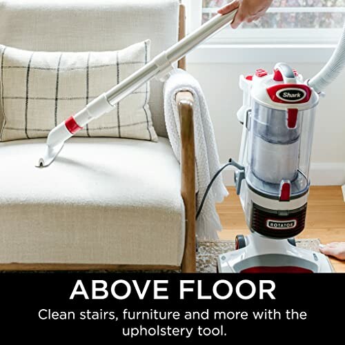 Vacuum cleaner with upholstery tool on armchair.
