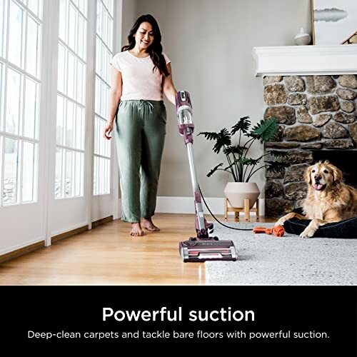 Woman vacuuming living room with a dog nearby